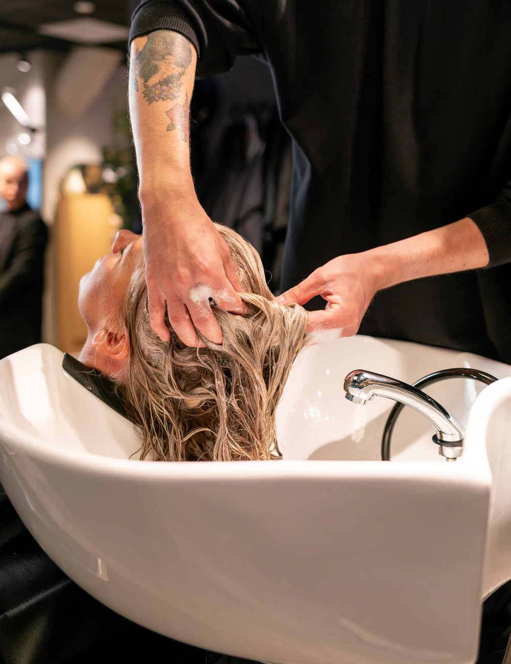 Leende kund i tvättstol hos Nikita Hair.