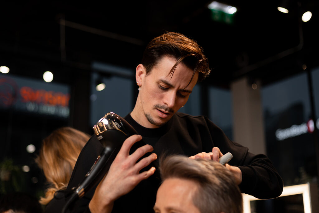 Professionell frisör stylar kund med fokus och precision i Nikita Hair-salong.
