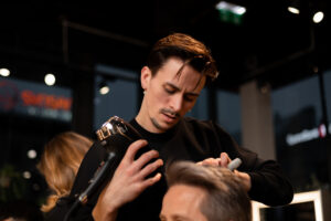 Professionell frisör stylar kund med fokus och precision i Nikita Hair-salong.