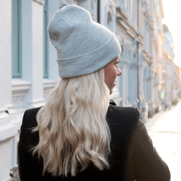 Kvinne med blondt hår og lue i vinterlys – typisk situasjon som kan gi statisk hår.