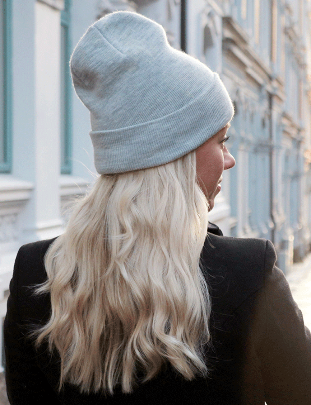 Kvinna med långt blont hår och mössa under en kall vinterdag – visar hur friktion kan skapa statiskt hår.