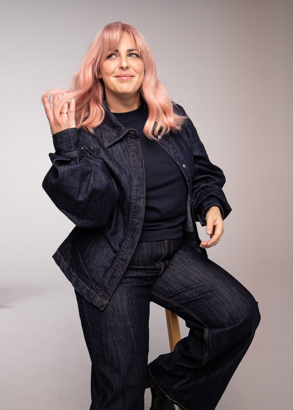 Modell med puderrosa hår och mjuka längder, sittande och stylat i en avslappnad, modern look