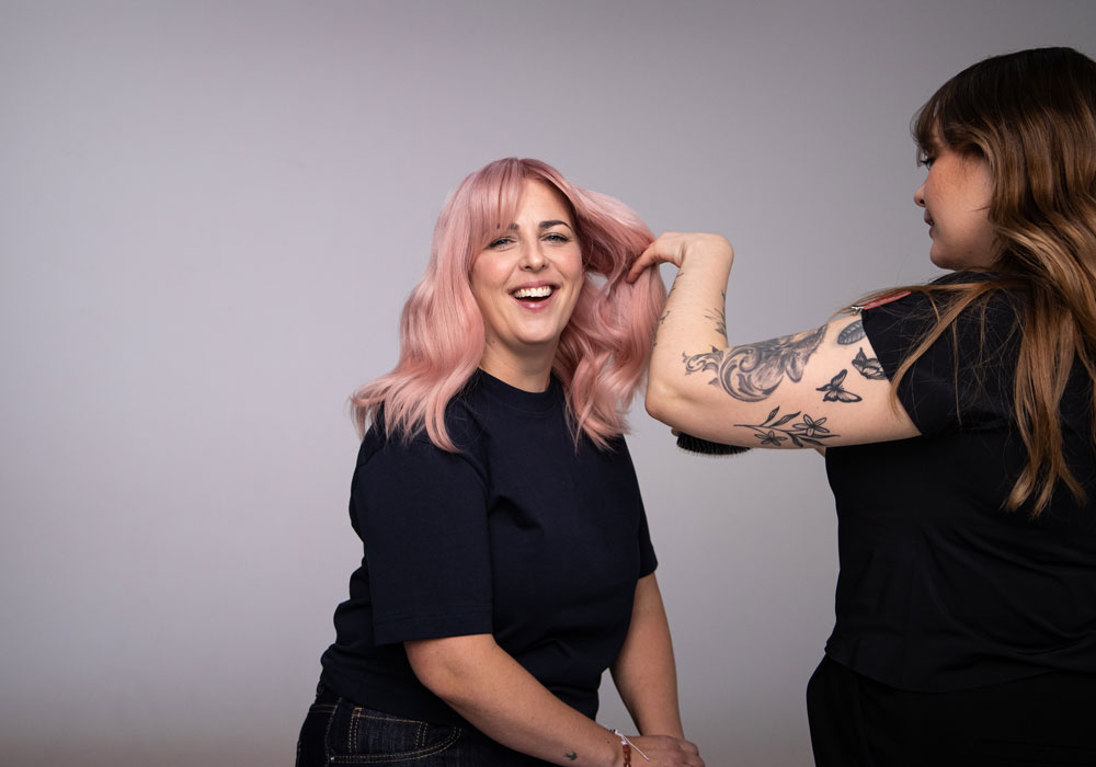 Styling av puderrosa hår med mjuka längder i salongmiljö